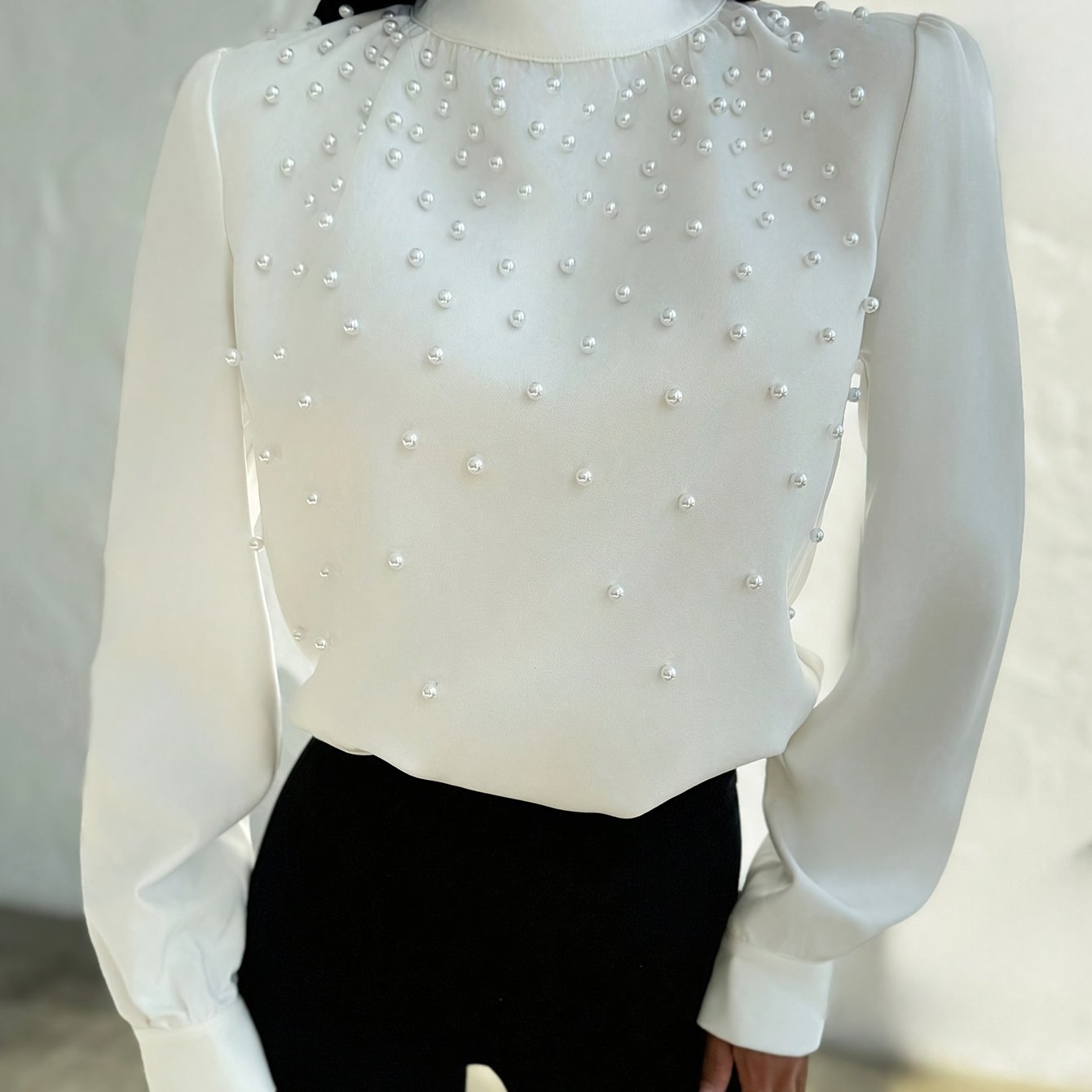 Blusa elegante para mujer con cuello adornado: camisa blanca de manga larga con botones de cuentas en la parte delantera y cuello alto estructurado.